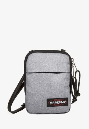 Szara torba na ramię z tkaniny o teksturowanej powierzchni, z zamkiem błyskawicznym, przednią kieszenią, regulowanym paskiem oraz akcentem logo w czerwono-czarnych kolorach.