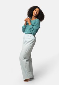 Turquoise langemouw overhemd en losse, lichtblauwe gestreepte broek. De outfit heeft een relaxte pasvorm en een zachte textuur.