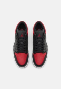 Baskets noires et rouges avec dessus en cuir et mesh, embout perforé, et Swoosh blanc contrastant. Caractérisées par des lacets noirs et des accents rouges.