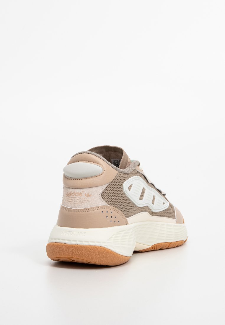 Scarpa atletica beige con sovrapposizioni in rete e sintetico, logo in bianco, design del tallone curvo e suola in gomma testurizzata.