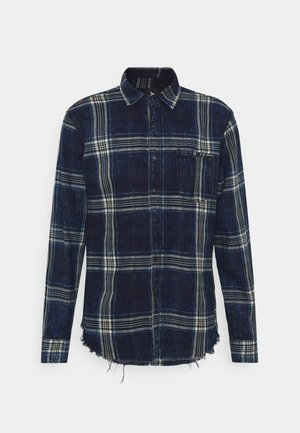 Chemise à manches longues à carreaux bleu marine et blanc avec boutons à l'avant, une poche poitrine et un ourlet effiloché en bas.