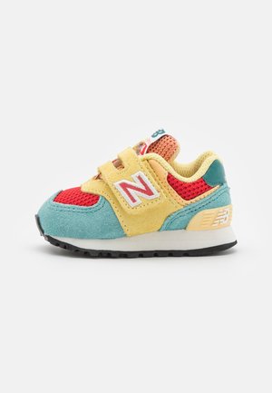 New Balance sneaker i børnestørrelse i turkis, rød, gul og orange med velcrobånd og sort gummisål.