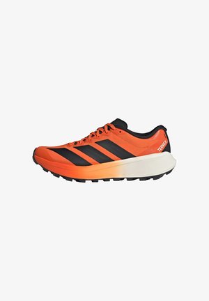 Zapatilla de trail running Adidas Terrex en naranja y negro con suela blanca gruesa y dibujo negro, vista lateral.