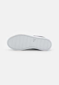Semelle de sneaker blanche avec texture nervurée et détail de logo subtile. Design épuré avec une finition lisse et une légère courbure au niveau de la zone des orteils.