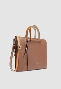 Bolso tote de cuero marrón con dos asas superiores y una correa de hombro ajustable, que presenta un bolsillo con cremallera en la parte frontal y detalle del logo en dorado.