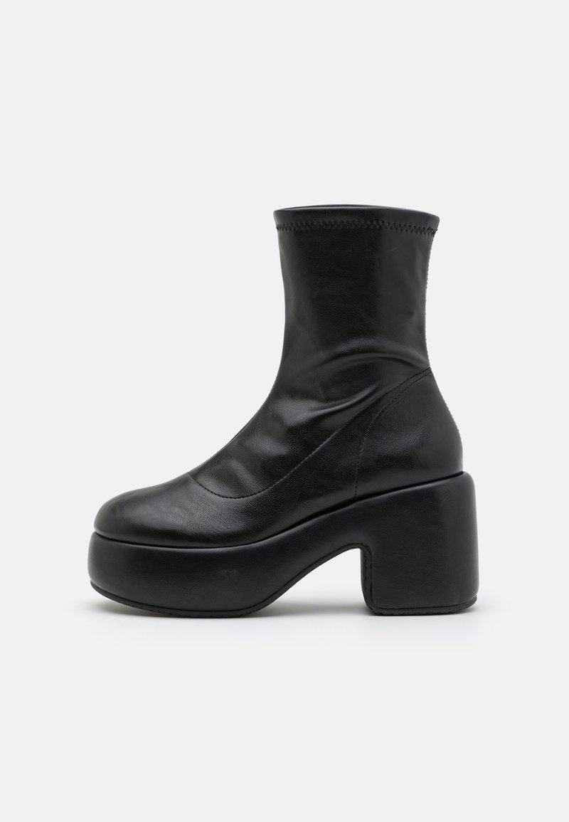Bottine en cuir noir à semelle à plate-forme épaisse et talon carré, finition lisse et tige supérieure légèrement extensible.