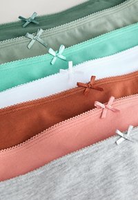 Pile de sous-vêtements en coton pour femmes en vert, menthe, blanc, marron, rose et gris avec de petits nœuds sur les bords de la ceinture.