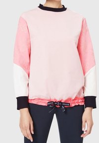 Sweat-shirt rose avec accents noirs, épaules tombantes et ourlet élastiqué. Présente un design texturé sur les manches et un cordon de serrage ajustable.