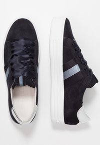 Marina mockasnörskor i mocka med satinband, prydda med ljusblå och svarta ränder. Vit gummi-sula och metallisk klack ger kontrast.