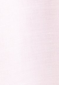 Tissu texturé rose clair avec motif tissé visible et détails de couture subtils.
