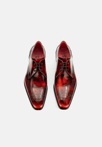 Rote Leder-Halbschuhe mit spitzen Zehen, aufwendigen schwarzen floralen Gravuren und schwarzen Schnürsenkeln. Glatte Oberfläche und schlanke Silhouette.