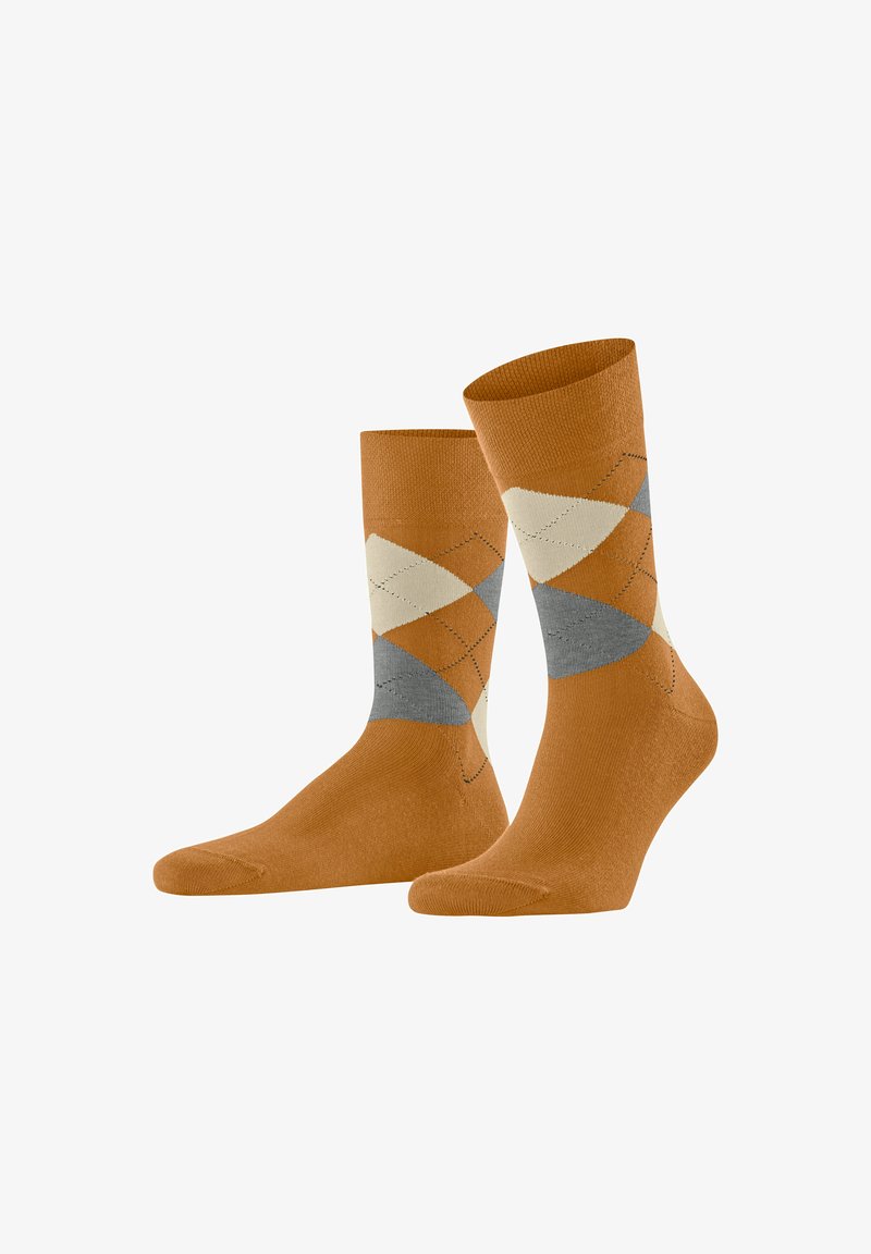 Une paire de chaussettes mi-mollet couleur orange brûlé avec un motif de losanges argyle beige, gris et marron au niveau de la cheville et du bas de la jambe.