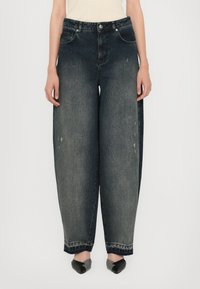 Jeans in denim nero sbiadito a gamba larga, con vita alta, tasche frontali e leggere abrasioni. L'orlo presenta bordi sfrangiati.
