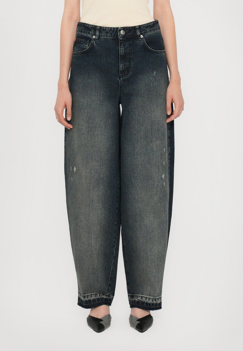 Jeans in denim nero sbiadito a gamba larga, con vita alta, tasche frontali e leggere abrasioni. L'orlo presenta bordi sfrangiati.
