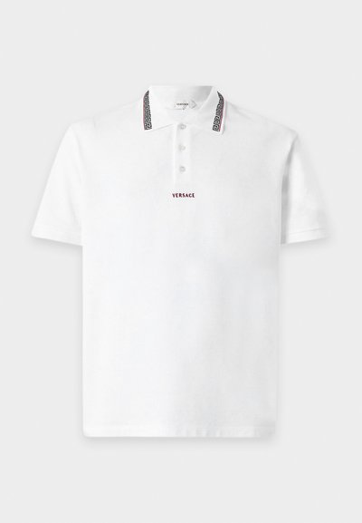 Polo blanc à manches courtes avec trois boutons, logo Versace brodé en rouge sur la poitrine, et bordure noire à motifs sur les bords du col.