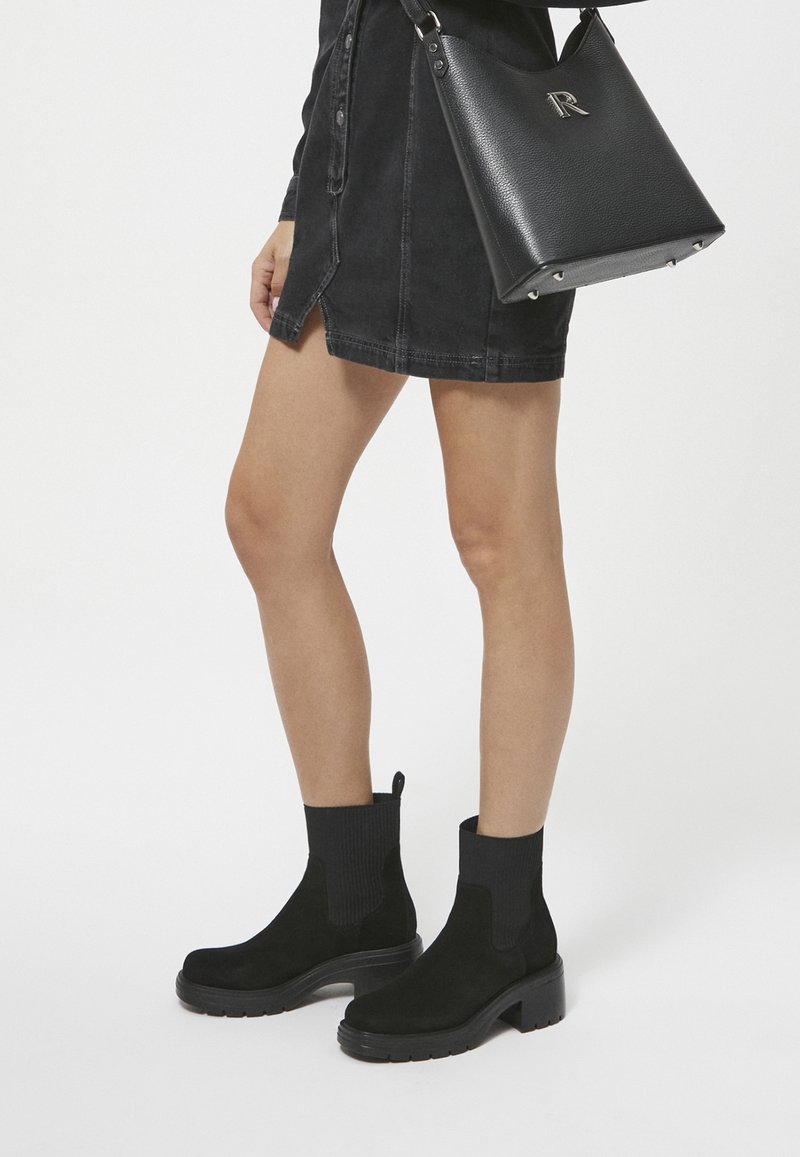 Black suede ankle boots with ribbed sock collars and chunky rubber soles, paired with a black handbag featuring a logo detail.
