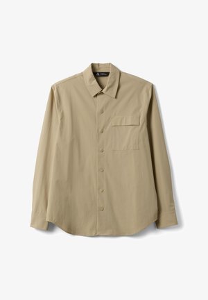 Camisa beige de manga larga con botones, un bolsillo en el pecho y cuello clásico, presentada extendida sobre un fondo blanco.