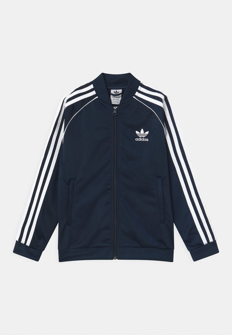 Chaqueta deportiva Adidas azul marino con diseño de tres rayas blancas en las mangas, cremallera frontal y dos bolsillos laterales. Fabricada con material liso y ligero.