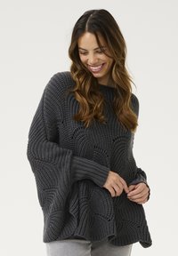 Suéter gris de punto con un patrón texturizado en ondas y mangas anchas. Los puños y el dobladillo acanalados añaden detalle al diseño.