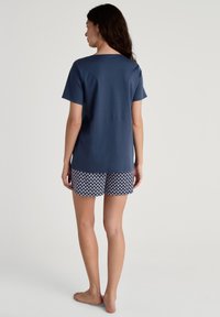 Marineblauwe T-shirt met korte mouwen, gecombineerd met gestreepte shorts in wit en marineblauw, met een comfortabele pasvorm en zachte stof.