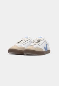 Sneaker bianchi con dettagli in suede beige, logo blu "VEJA", design con lacci, suola in gomma testurizzata e forma complessiva bassa.