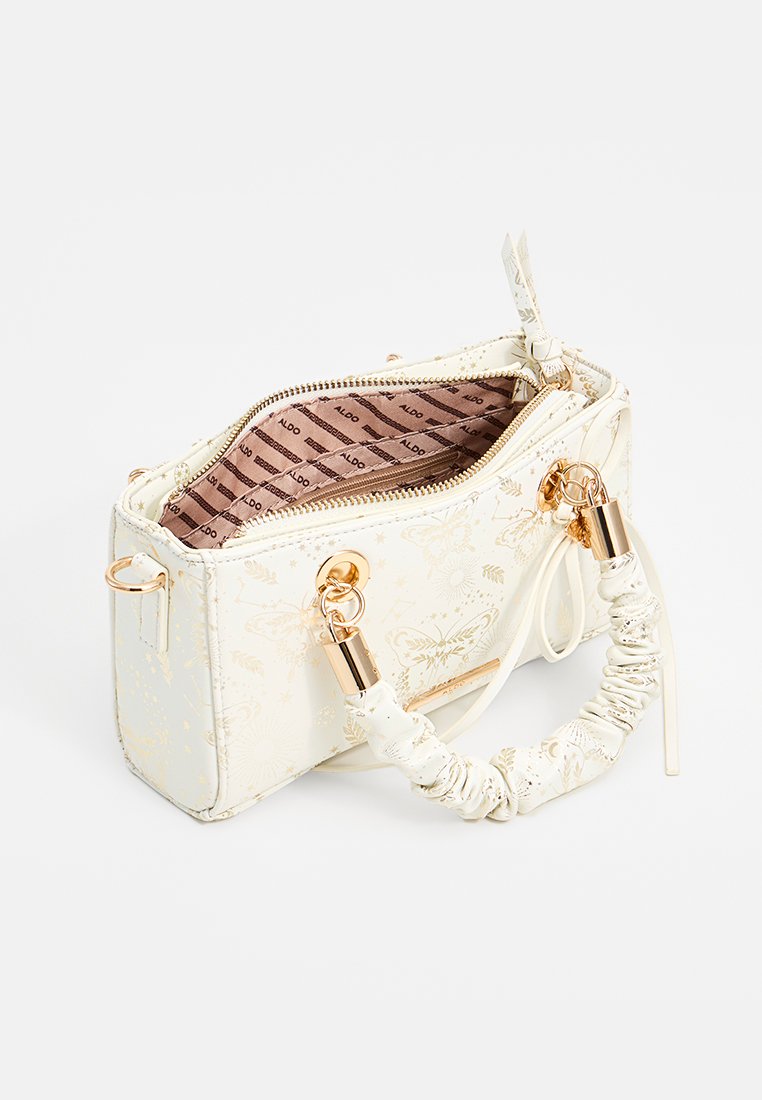 Sac à main blanc avec un motif floral doré, fermeture à glissière et une poignée texturée. Comprend des accents dorés et un intérieur doublé en tissu.