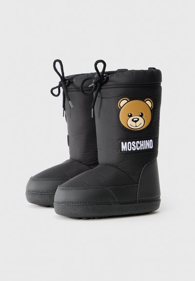 Svarta vadderade vinterkängor med en björnfans patch och "MOSCHINO"-etikett. Utrustad med gummisula och justerbara snören i toppen. Slät textur.