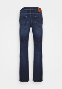 Jeans din denim albastru închis, cu picior drept, talie medie, cusături subtile pe buzunarele din spate și o etichetă de marcă din piele maro.