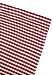Crvena i bijela prugasta rebrasta tkanina s mekanom teksturom, s malim logotipom sa strane. Pruge su ravnomjerno raspoređene.