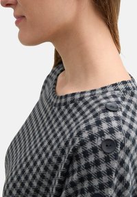 Maglione in grigio e nero a scacchi houndstooth con scollatura ampia, caratterizzato da quattro bottoni neri sulla spalla per un tocco di dettaglio e texture.