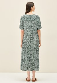 Vestido largo verde con estampado y mangas cortas, que presenta un diseño geométrico en blanco, con un dobladillo con volantes en capas y un ajuste relajado.