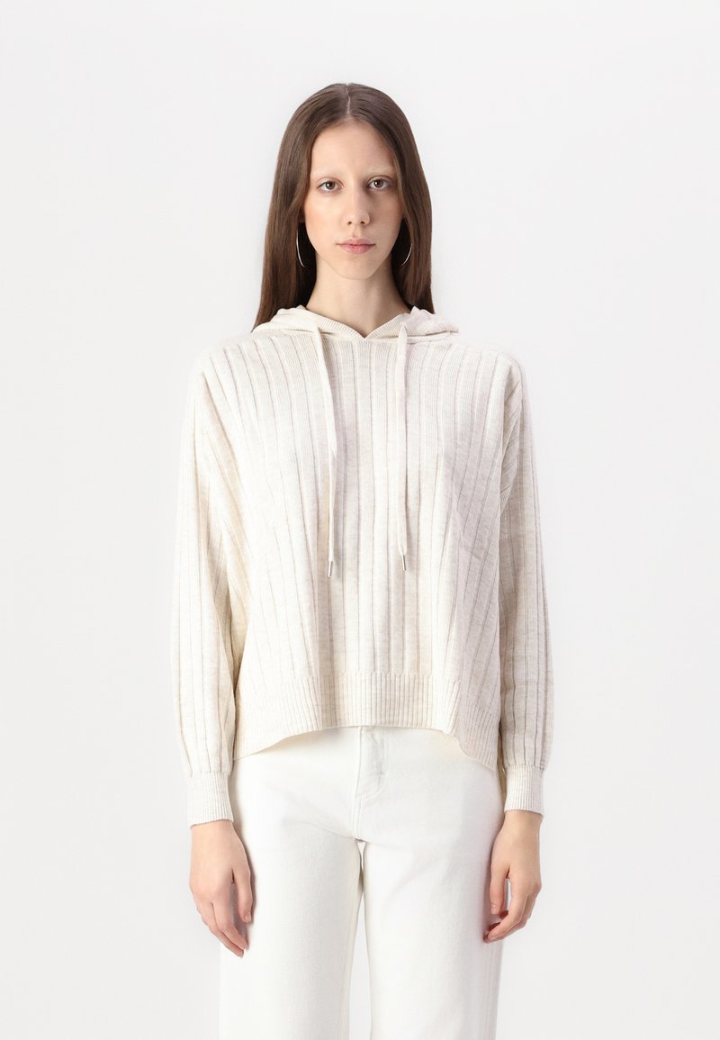 Hellbeige, gerippter Hoodie mit einer Kängurutasche vorne, Kapuze mit Kordelzug und lässiger Passform. Kombiniert mit weißen Hosen aus texturierter Stoff.