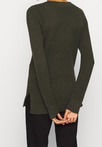 Maglione lavorato a maglia verde scuro con maniche lunghe, scollatura rotonda e spacchi laterali all'orlo per un tocco di dettaglio e comfort.