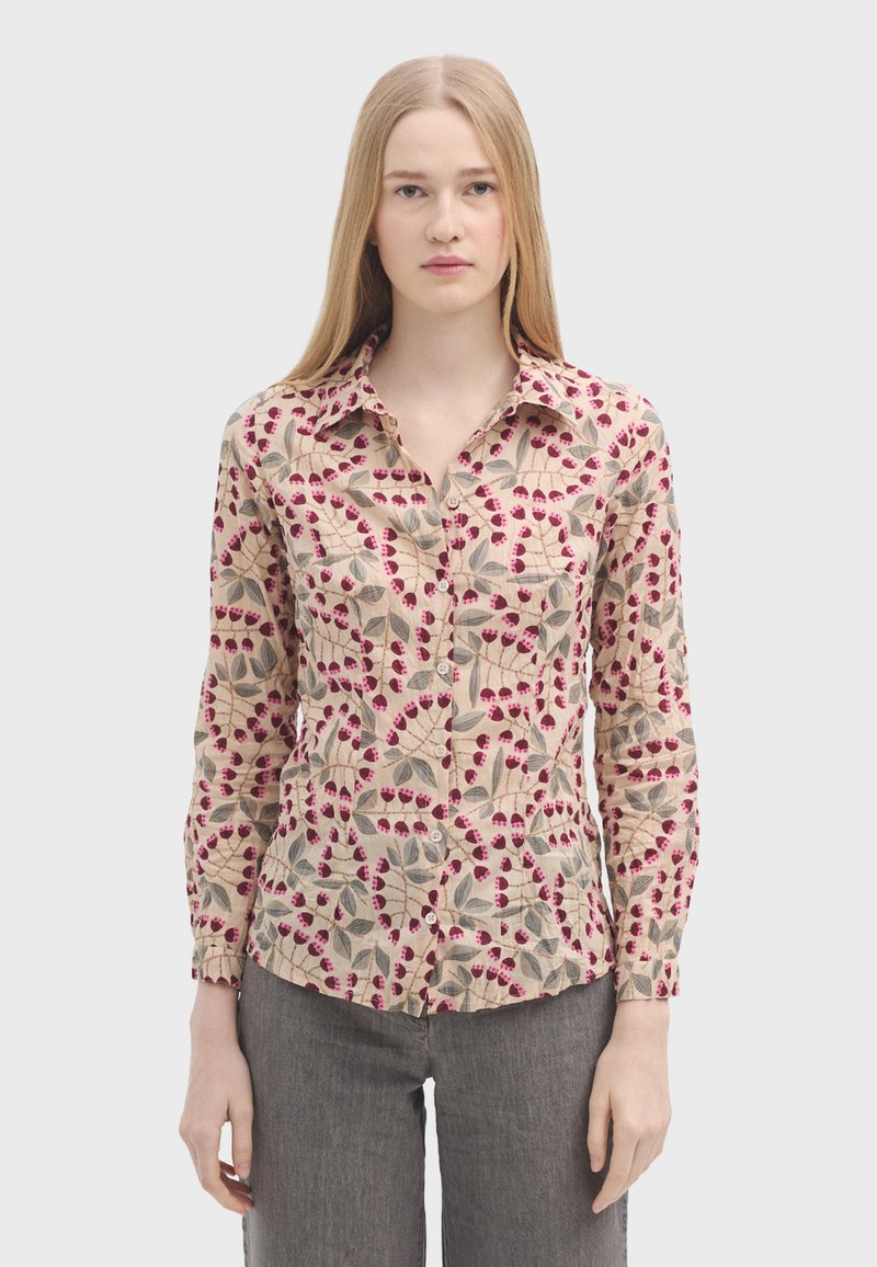 Langærmet skjorte i let stof med en beige baggrund, der har et blomsterprint i rød og grøn. Knappet front og krave.