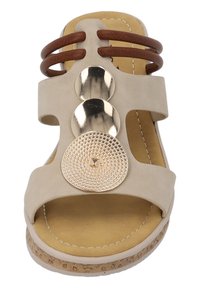 Sandal beige con fasce larghe e dettagli in legno marrone. Presenta decorazioni circolari metalliche, dettagli testurizzati e una suola simile al sughero.