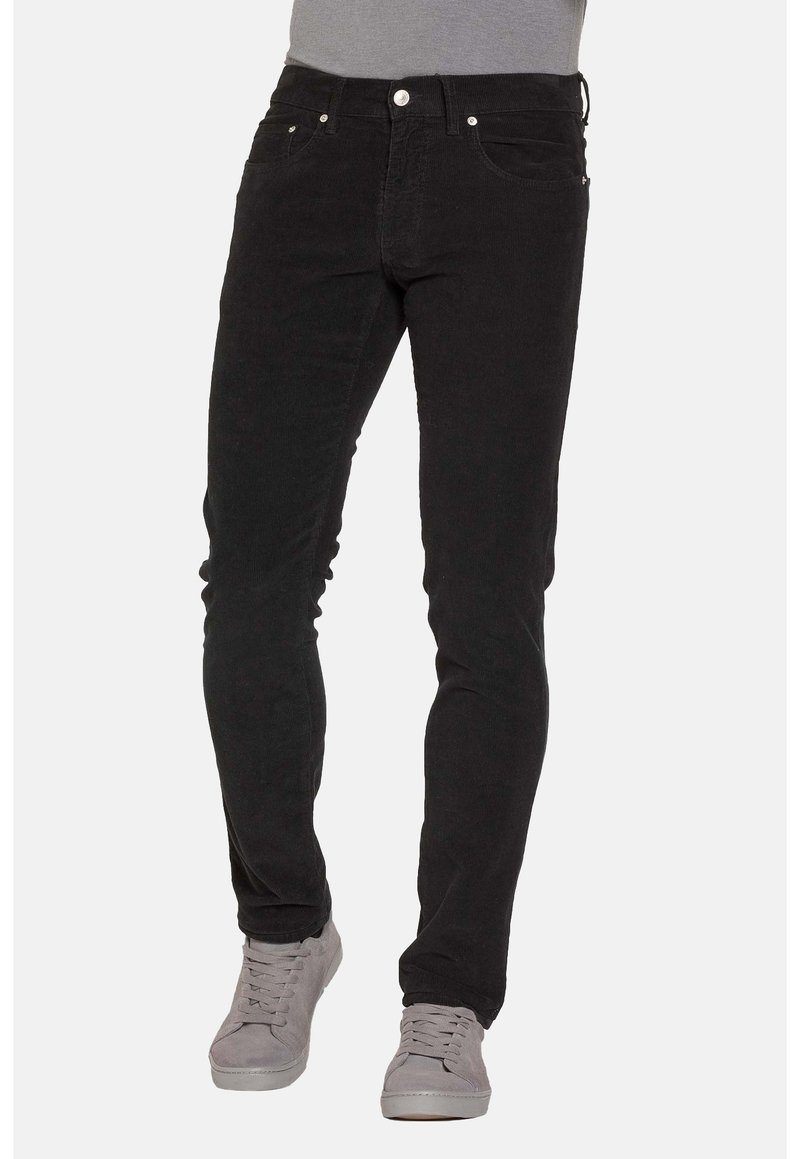 Jeans skinny in corduroy nero con una texture liscia, cinque tasche e hardware argentato, abbinati a sneakers casual grigie.