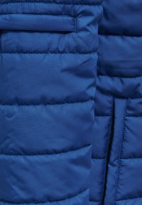 Chaqueta de plumas azul con un diseño acolchado y costuras horizontales, una textura suave y un bolsillo lateral con cremallera oculta.