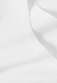 Tissu en coton blanc à texture lisse, présentant de subtils motifs de tissage diagonal et un tombé doux, adapté à diverses applications textiles.