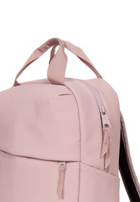 Mochila de un suave color rosa claro con un acabado mate. Cuenta con un cierre de cremallera, asas superiores y tiradores de cremallera texturizados para un acceso fácil.