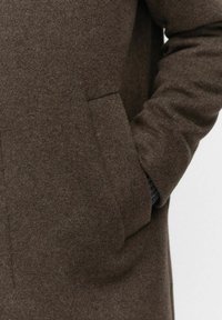 Bruine wollen jas met een gestructureerde afwerking, voorzien van een zijzak en een effen kleur. De stof lijkt dik en warm.