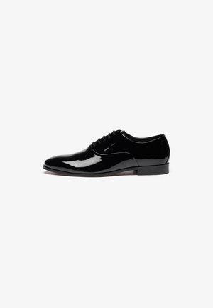 Chaussure habillée en cuir verni noir avec un design élégant, un bout rond et un petit talon. Elle dispose d'un système de laçage et d'une texture de surface lisse.