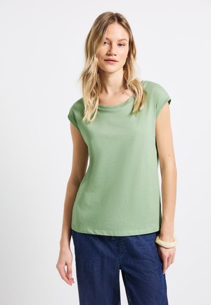 Lichtgroen shirt met korte mouwen en een ronde hals, gemaakt van zachte stof. Gecombineerd met donkerblauwe wijde broek, met een gladde textuur.