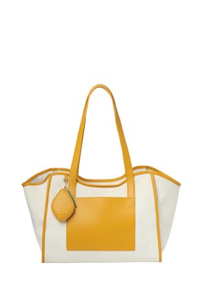 Torba typu tote w kolorze kremowym i musztardowym z dwoma długimi uchwytami, przednią kieszenią oraz małą, przymocowaną sakiewką na monety zawieszoną na jednym uchwycie.