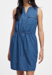 Denimové šaty bez rukávů s výstřihem do V, zapínání na přední knoflíky, dvě náprsní kapsy, elastický pas a šňůrka v pase, v středně modré barvě.