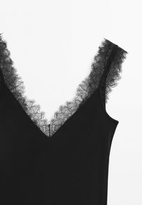 Black sleeveless top with a V-neckline trimmed in delicate floral lace along the neckline and straps.