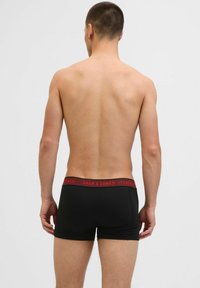 Schwarze Boxershorts mit rohem elastischem Bund, auf dem "JACK & JONES" steht. Glatte Textur, enganliegende Form und mittellange Beine bis zum Oberschenkel.