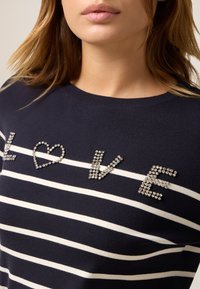 Maglione a righe navy con righe bianche, decorato con lettere di strass che formano "LOVE" e un cuore, scollo rotondo e texture morbida.