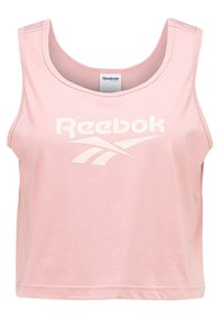 Růžový bezramínkový crop top vyrobený z hladkého materiálu, s velkým bílým logem "Reebok" na přední straně a kulatým výstřihem.