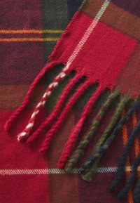 Manta xadrez vermelha com bordas franjadas; apresenta uma mistura de linhas verde-escuro, azul-marinho e amarelo em tecido macio e texturizado.