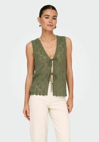 Sukienka bez rękawów w oliwkowym kolorze z dekoltem w kształcie litery V i z przodem wiązanym, posiadająca falbaniaste wykończenie i skomplikowany wzór z koronki.